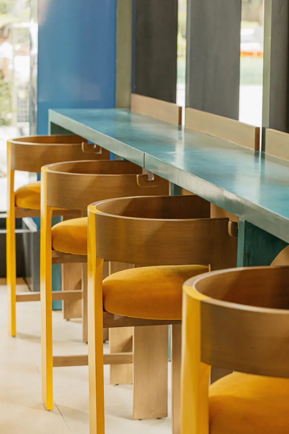 Curved timber chairs with yellow seats at the window bar