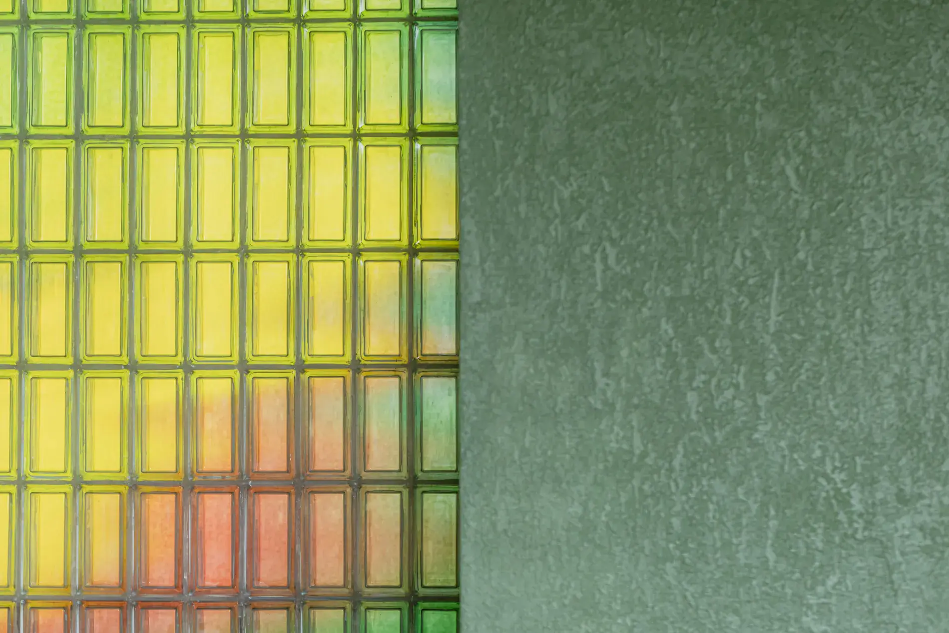 Glass-block wall glowing yellow against sage plaster