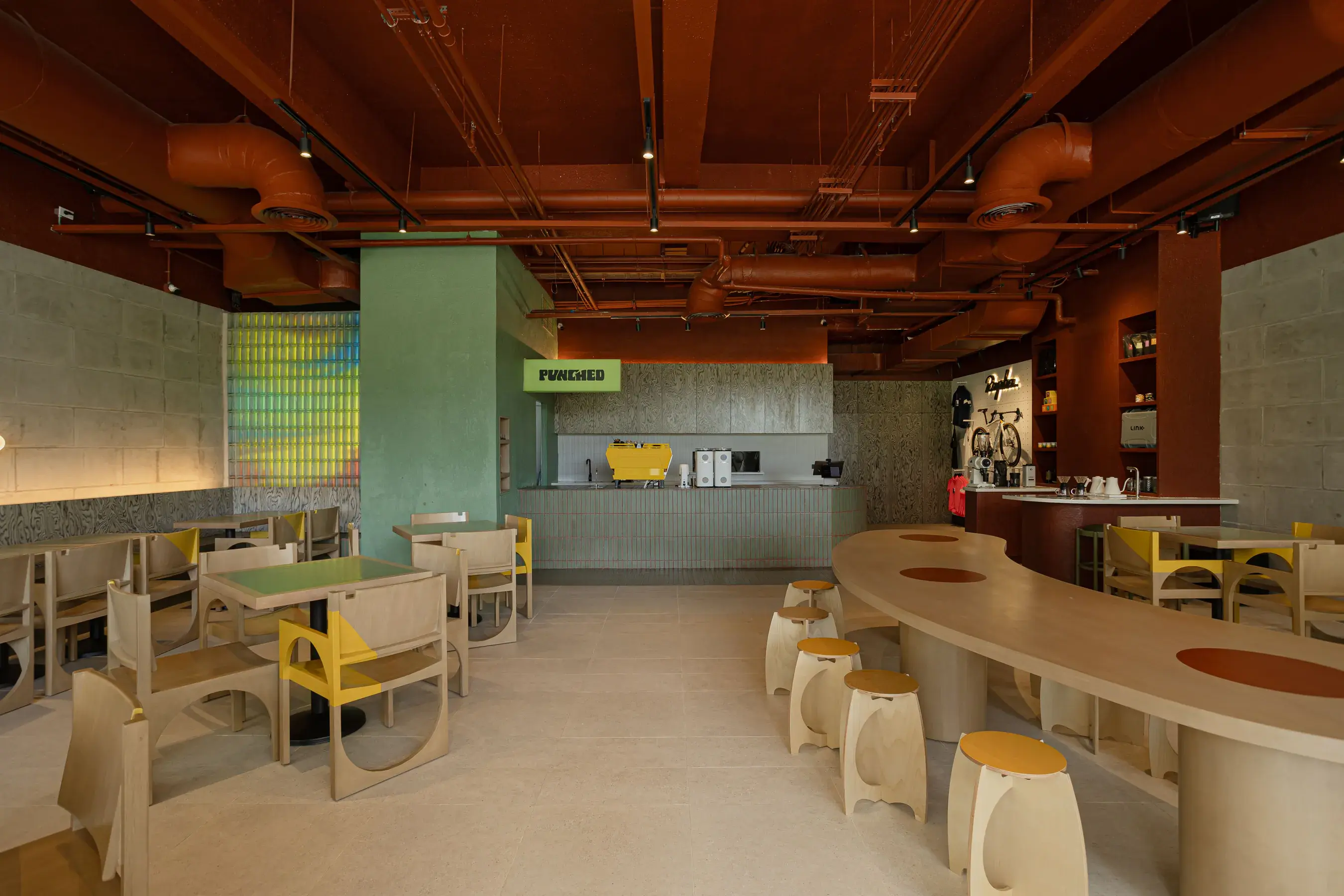The Mabuhay Tower dining room: terracotta ceiling, glass-block wall, yellow chairs and the lit Punched sign over the counter