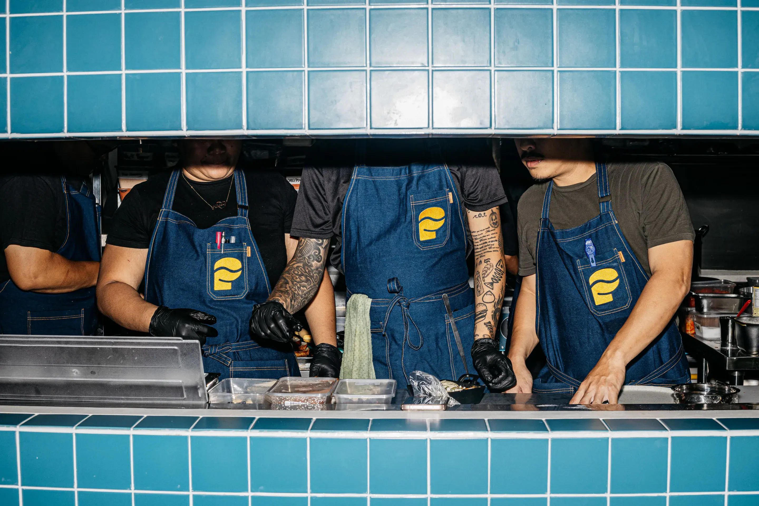 The Punched crew in denim aprons working the blue-tiled pass at Johndorf Tower